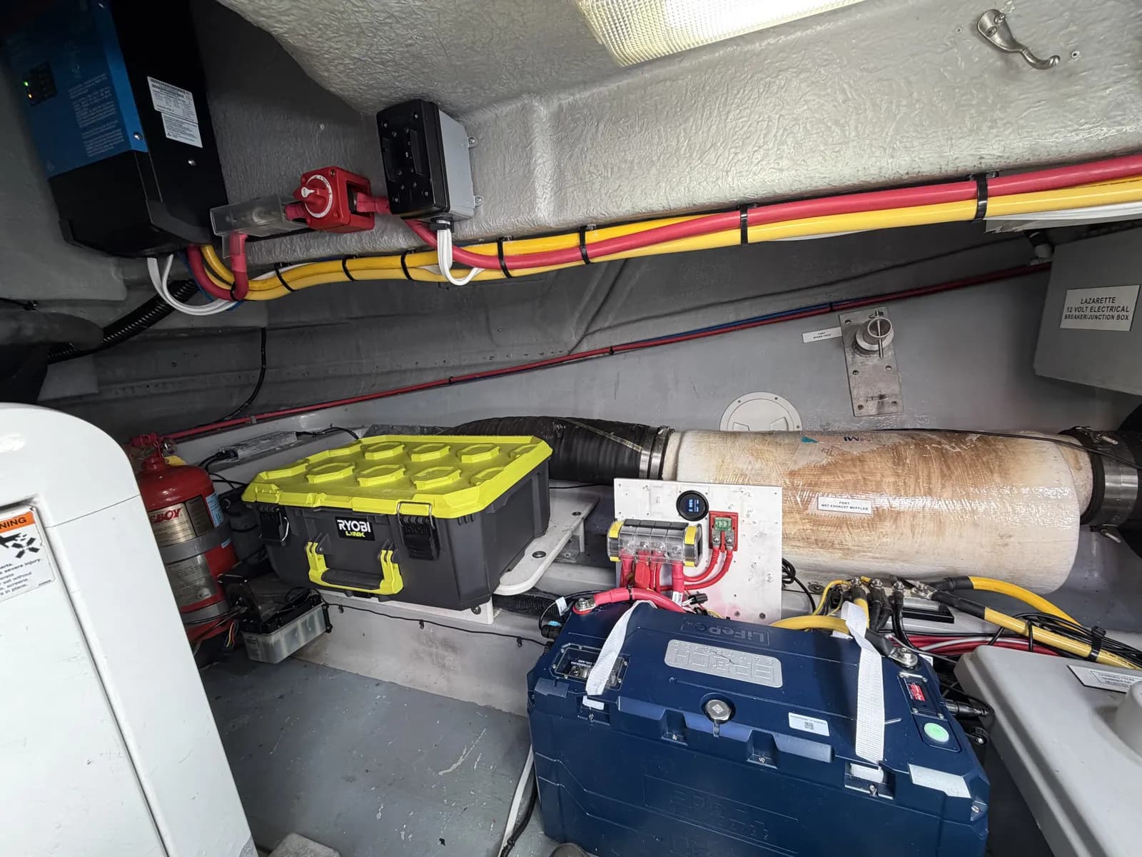 LiFePO4 lithium battery installed and strapped in a lazarette, with battery switch, fusing and a Victron inverter/charger mounted above.