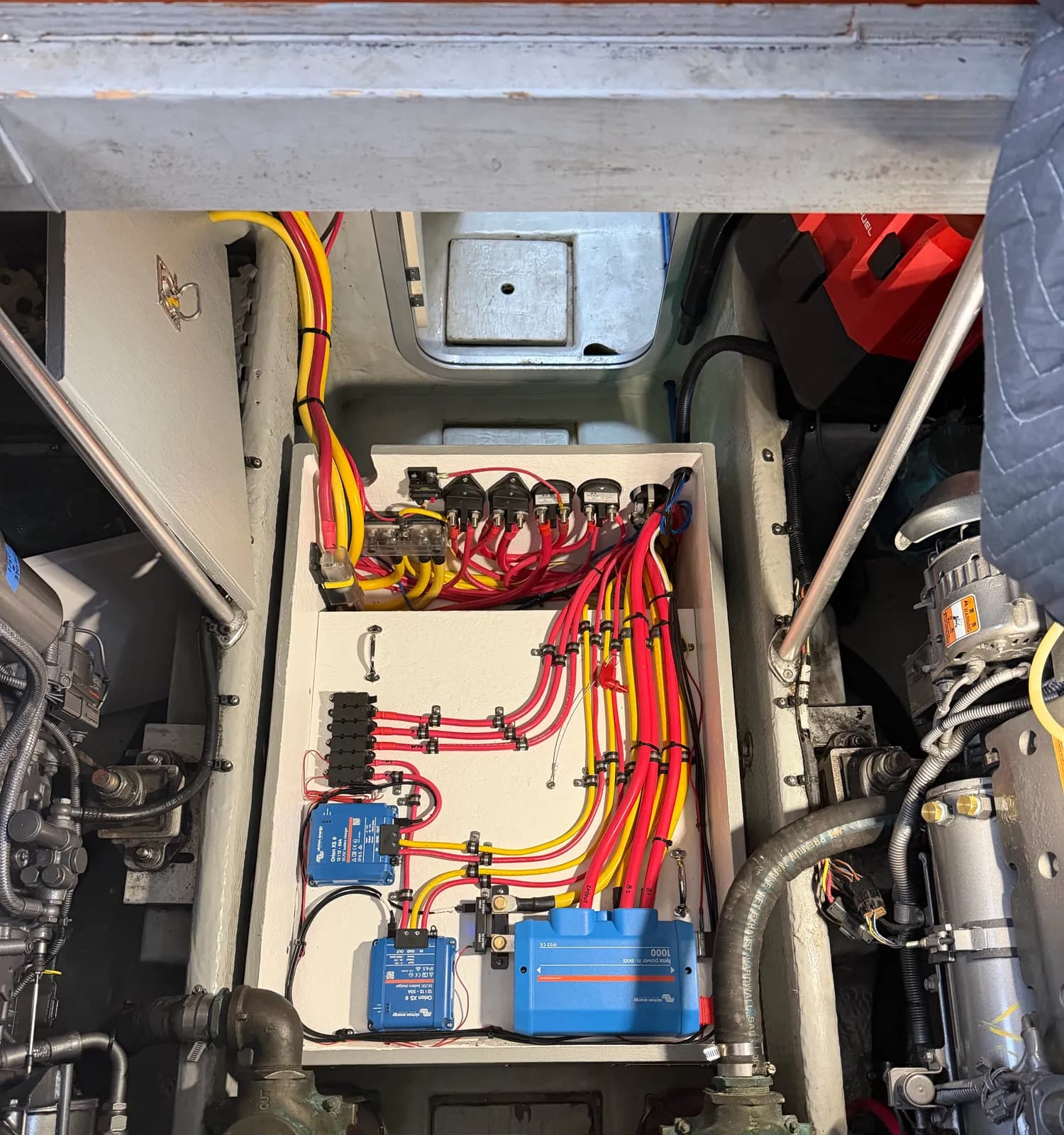 Engine-room DC distribution panel with Victron Orion DC-DC chargers, fused busbars and neatly clamped red and yellow cable runs.