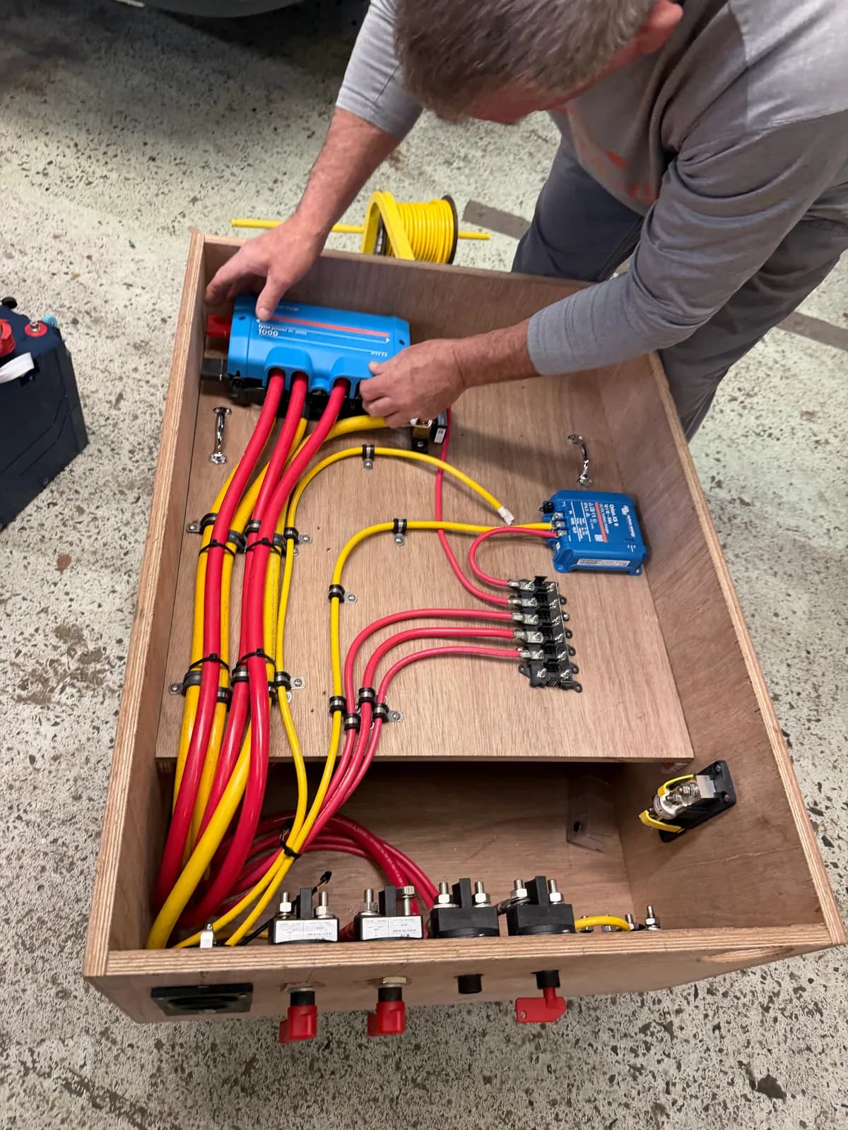 Marine Electric technician pre-building a DC distribution panel with Victron components in the shop before installation.